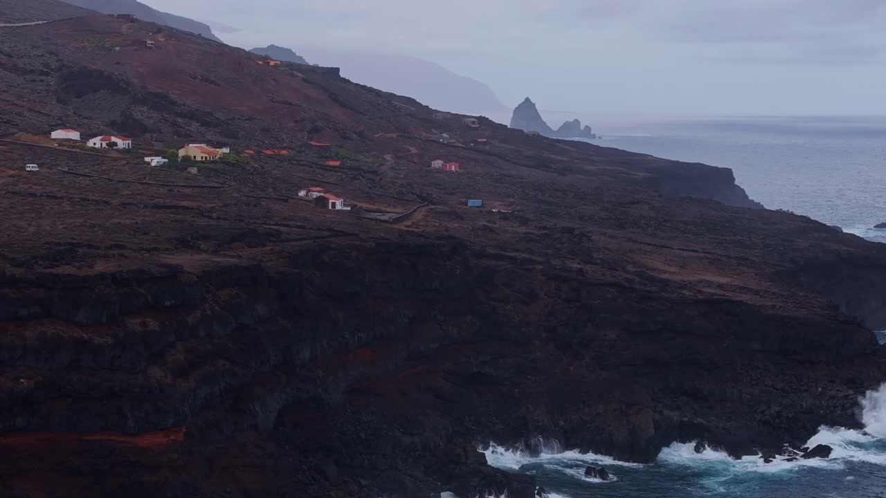 Aerial view reveals volcanic terrain and isolated homes on El Hierro coastline