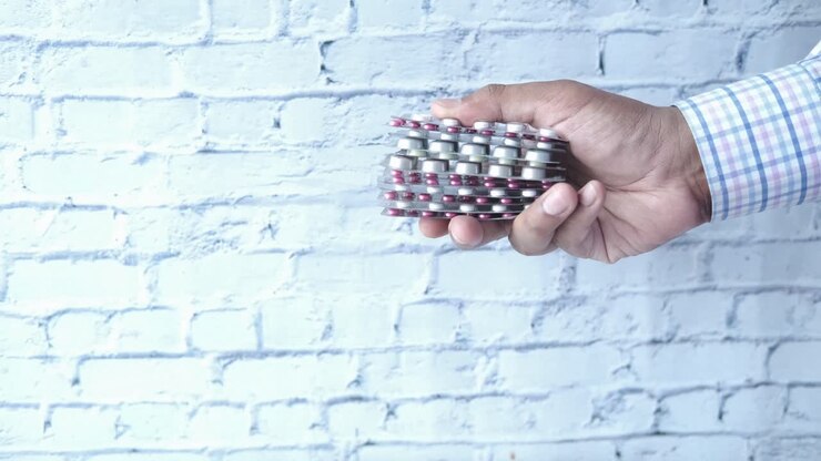 hand, die einen stapel blisterverpackungen mit verschiedenen pillen hält