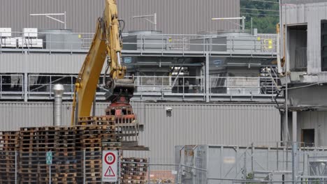 una potente excavadora con garra hidráulica que coloca escombros en un gran contenedor de basura en un sitio de demolición en suiza