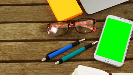 portátil, nota adhesiva, teléfono móvil, bolígrafo, organizador y gafas en la mesa 4k