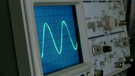 amplitude diagram on the oscilloscope. a man presses the buttons on the device. the geometric line changes shape