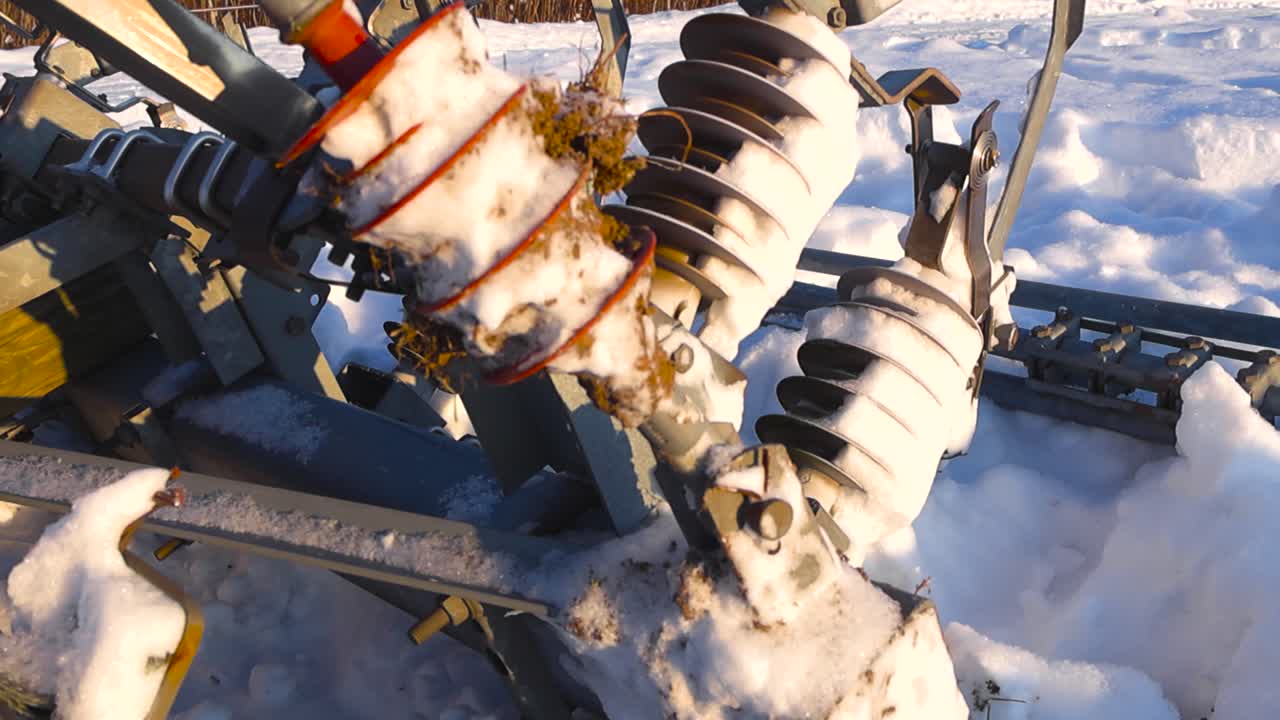 Side angled close view of high voltage railway insulators buried in thick snow, with frost and ice highlighted by warm winter sunlight and visible power cables in the background