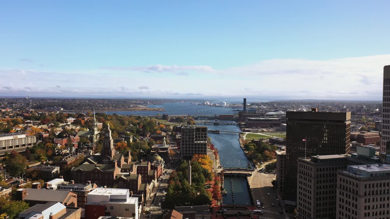 로드아일랜드 주 프로비던스 시내의 모샤수크 강과 프로비던스의 강을 따라 고층 건물 위를 날아다니며 굴, 다리, 풍력 터빈, 교회 첨탑이 있습니다.