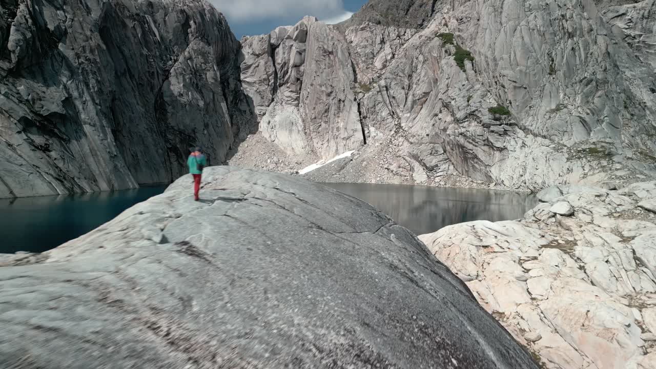 dos excursionistas que llegan a una remota laguna azul rodeada de grandes paredes de granito