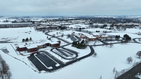 Toma-Aérea-De-Un-Campus-Escolar-Americano-Cubierto-De-Nieve