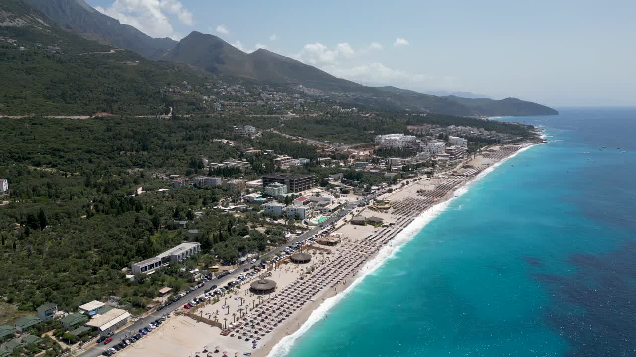 Bela praia na Riviera Albanesa com hotéis e montanhas ao fundo