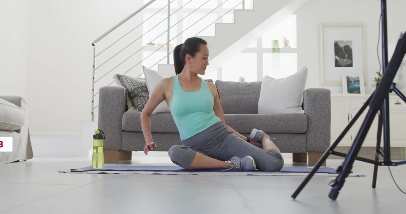 Fitness coach starting cam and social icons popping around her while guiding stretches on yoga mat