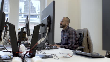 a middle-aged ethnic minority male is adjusting a computer screen and working in a library alone