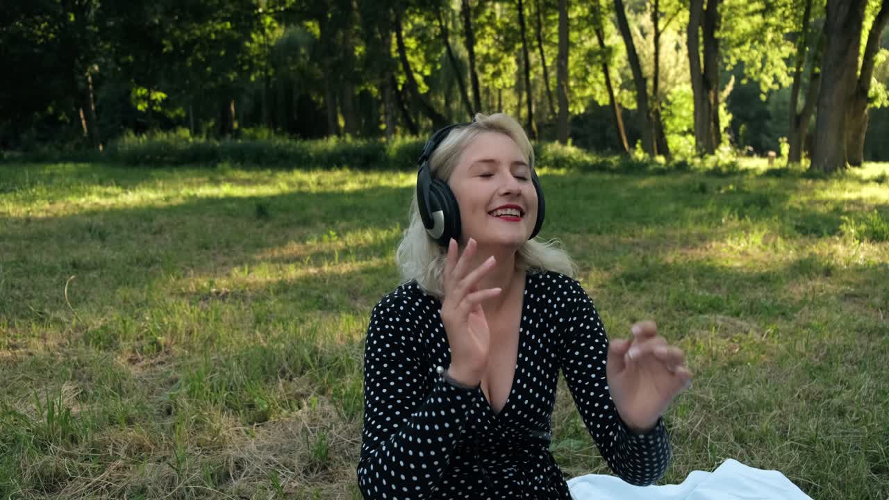 rubia en el parque bailando escucha música en auriculares