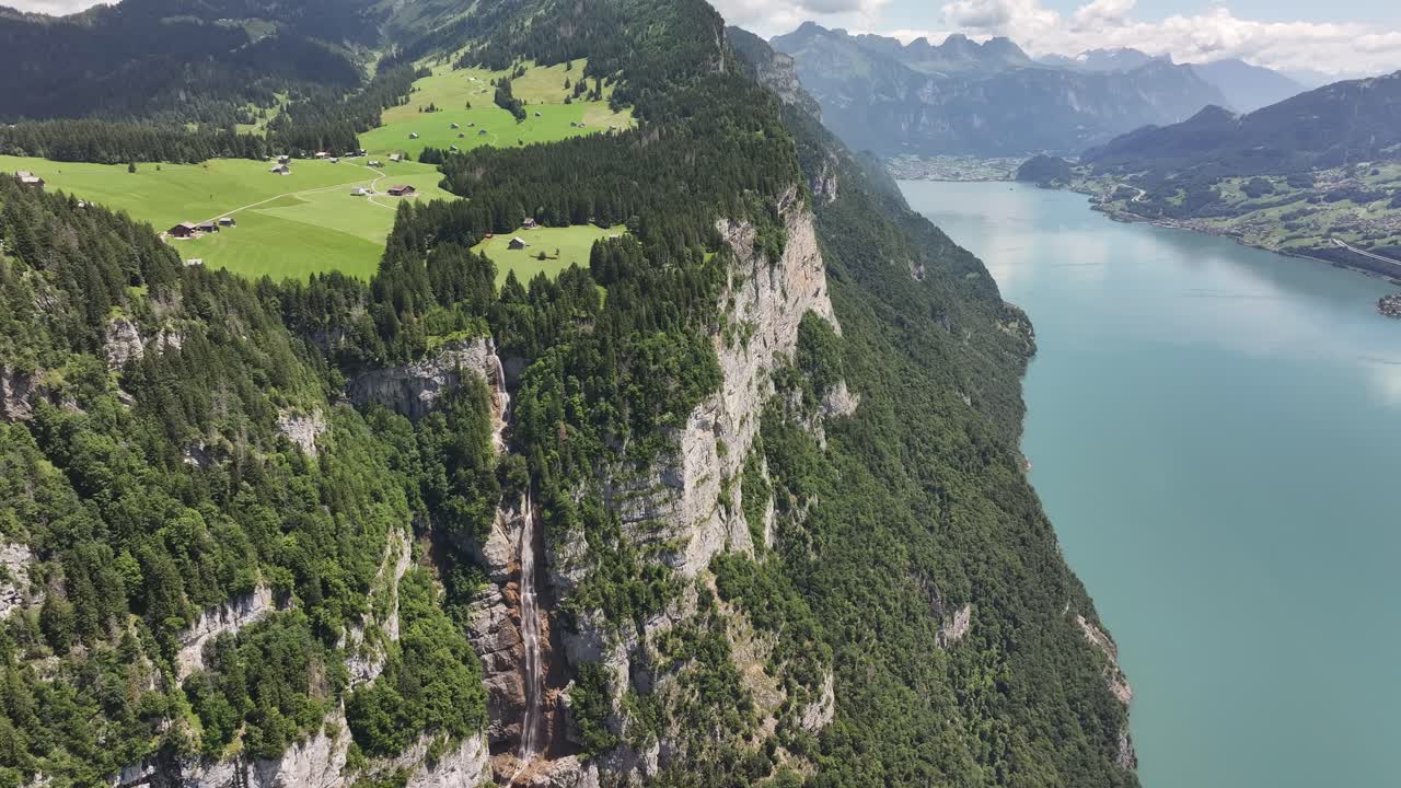 Aerial view of Seerenbach Falls, steep cliffs, green meadows, and Walensee lake in Switzerland