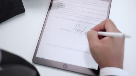 close up businessman hand working electronic signature on tablet by stylus. write business agreement of contract. man signing contract on tablet. business and technology concept.