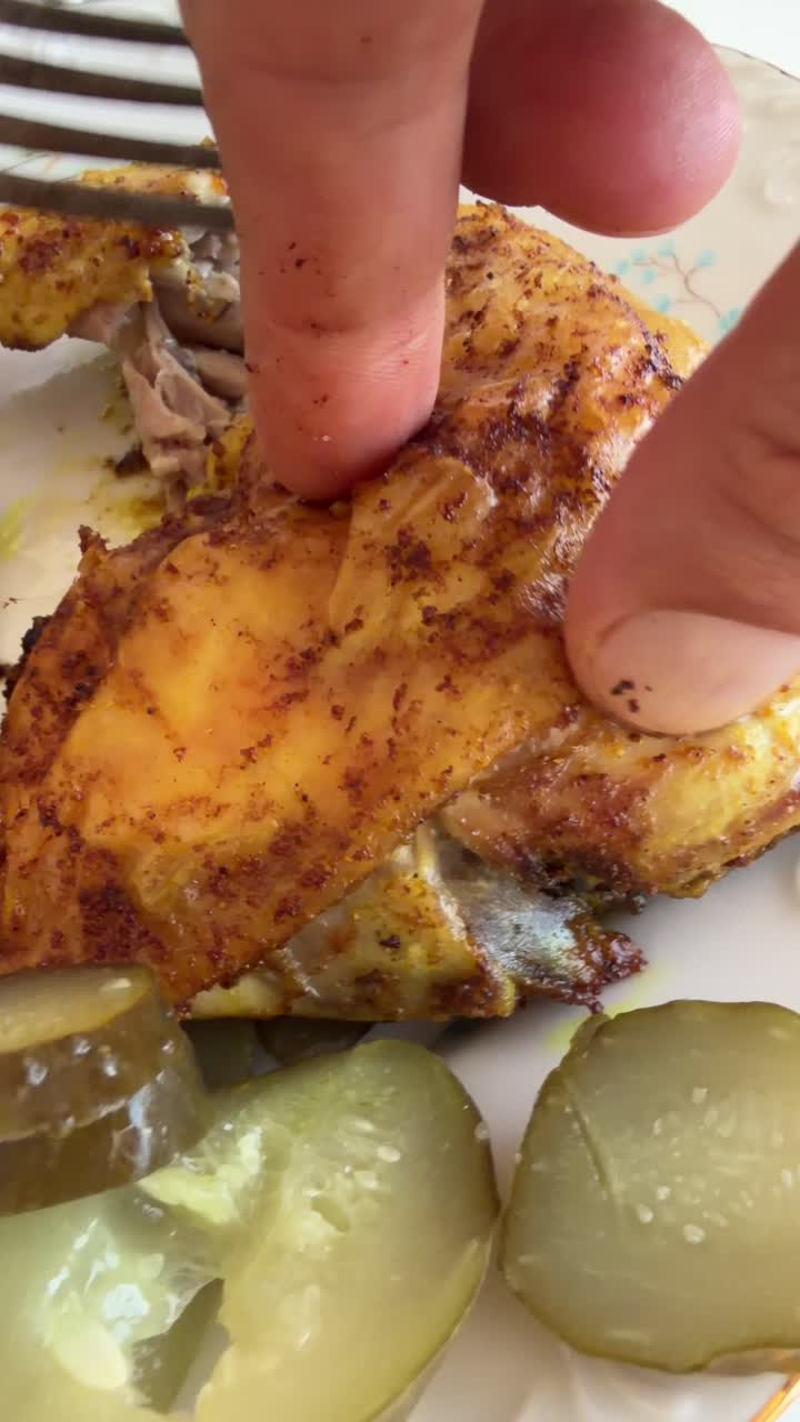 Primo piano di una mano che pela la pelle da pollo cotto