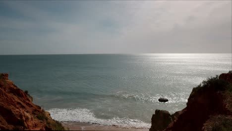 Early-morning-sunlight-shines-on-the-water-and-rugged-seaside-landscape-of-Lagos,-Portugal-in-the-Algarve