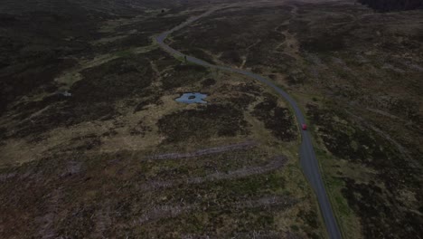 Un-Coche-Rojo-A-última-Hora-De-La-Tarde-Es-Capturado-Por-Un-Dron-Conducido-A-Lo-Largo-De-Una-Carretera-De-Vía-única