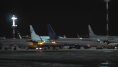 a blurred panoramic shot of airplanes on an airport courtyard at night