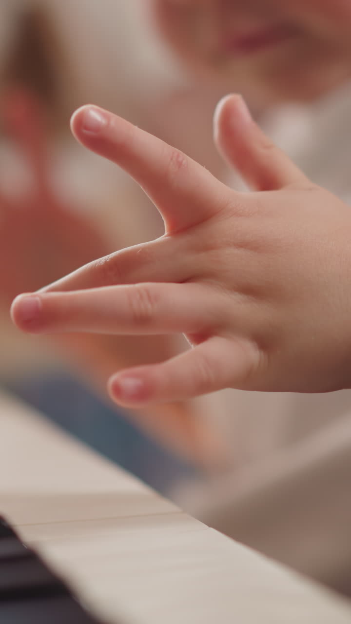 Small boy hand presses piano keys learning simple theme on blurry background closeup. Preschooler child takes classic musical lesson at home