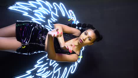 Glamour-ethnic-woman-dancing-in-studio-against-neon-wings