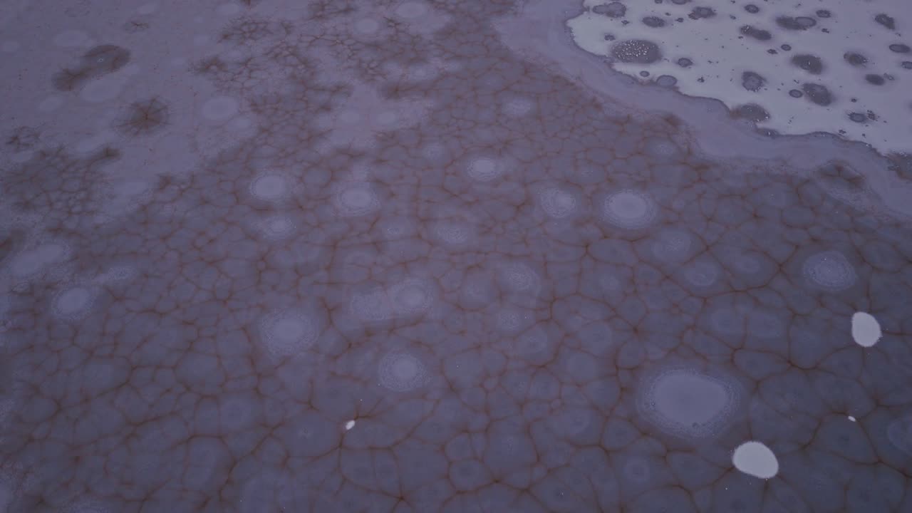 Motivi di ghiaccio circolari coprono un lago parzialmente ghiacciato - Drone in volo in avanti.
