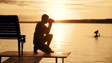 photographer taking picture of landscape during sunset. silhouette of people swimming in the river at sunset
