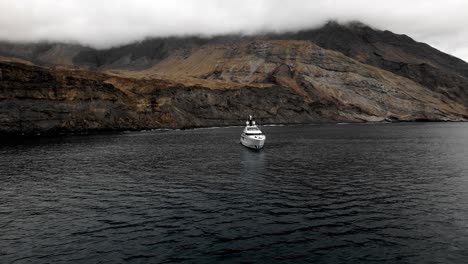 Superyacht-Vor-Anker-Vor-Einer-Mystischen-Insel-Mit-Klippen-Im-Hintergrund-Und-Tief-Hängenden-Wolken-Mit-Einer-Dunklen-Szene