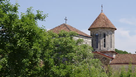 Motsameta-monastery-church-towers-rising-above-leafy-treetops,-Georgia