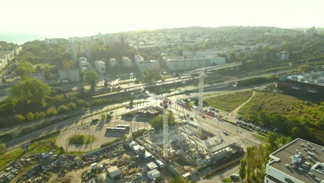 aerial drone shot of construction site with cranes among busy city streets and buildings