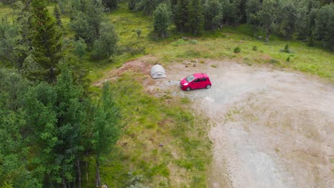 red car and a tent in a camping ground with vegetation in sweden