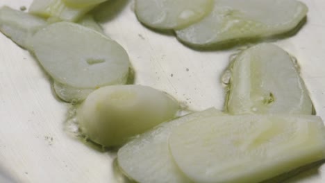 slices of garlic sizzling in oil in metallic frying pan during cooking