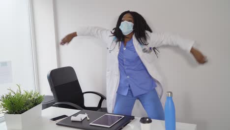 Black-female-doctor-in-medical-mask-dancing-in-clinic