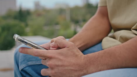 guy hands typing sms smartphone in green park close up. unknown man messaging