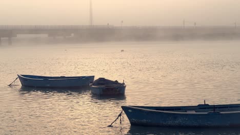 Fischerboote-Schweben-Anmutig-Auf-Der-Wasseroberfläche,-Umhüllt-Von-Der-ätherischen-Umarmung-Von-Nebel-Und-Nebel,-Und-Schaffen-Eine-Ruhige-Maritime-Atmosphäre