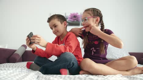 los niños se divierten con el teléfono móvil en casa. niña mostrando la lengua en una foto selfie