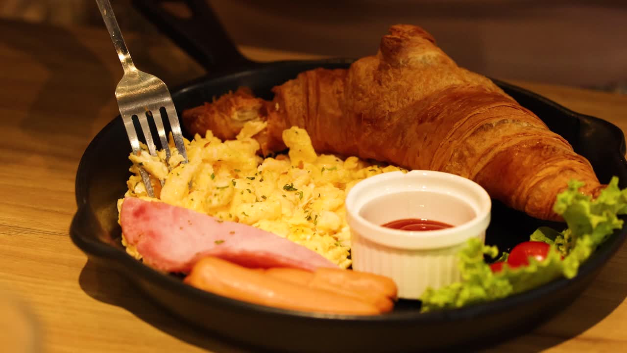 disfrutando de un desayuno de croissant con jamón y huevos