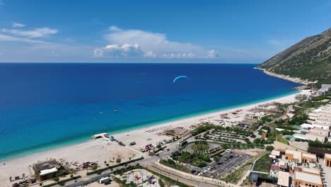 Aerial flyover of clear blue sea and white sand beach in Palase with gentle waves and homes