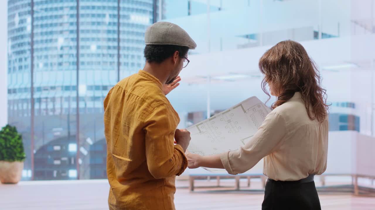 Business professional and real estate broker reviewing blueprints on laptop