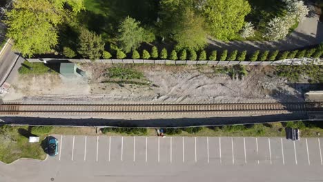 Aerial-rising-birds-eye-view-shot-of-car-park-and-train-track,-Massachusetts