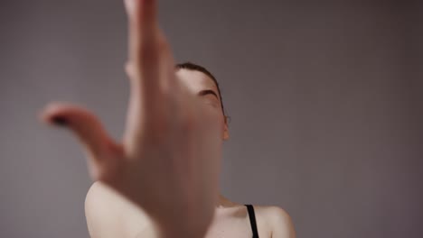 una mujer joven mira a la cámara, con la mano cubriendo su cara.