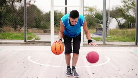 Close-Up-view-of-a-young-man-practicing-basketball-on-the-street-court.-He-is-playing-with-two-balls-simultaneously.-Slow-Motion