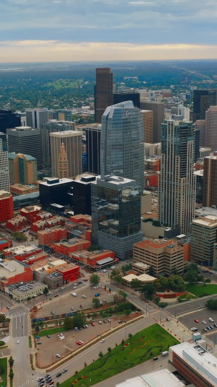 Approaching Denver skyscrapers in the city downtown. Lively traffic by the streets of the metropolis from top view. Vertical video