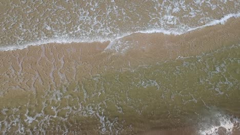 vista aérea de pequeñas olas del mar báltico y arena bajo el agua