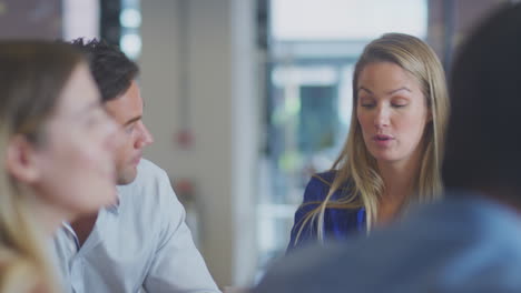 close-up del equipo de negocios teniendo una reunión sentado alrededor de la mesa en una oficina moderna de plan abierto