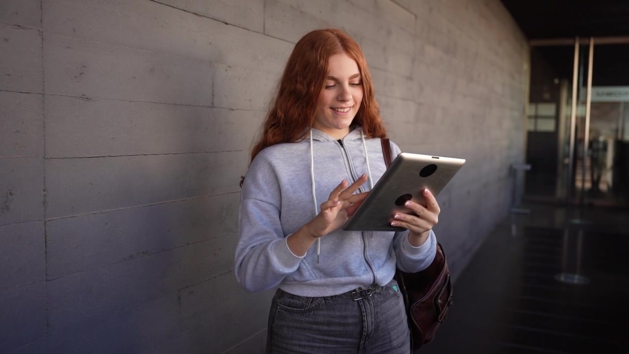 A smiling young woman with beautiful red hair wearing a casual hoodie and enjoying life