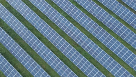 Top-down-aerial-of-a-lot-of-solar-panels-in-a-green-field