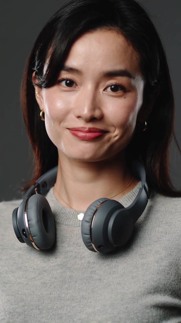 Vertical video: Turning woman shifting to camera as camera rolling in studio showcasing headphones
