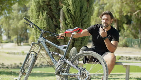 hombre feliz con discapacidad sentado en un banco con la pierna en la bicicleta