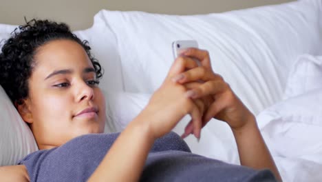 Woman-using-mobile-phone-while-lying-on-bed-4k