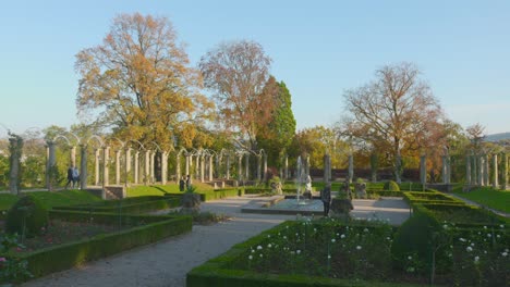 Schlossgarten park in Stuttgart with people strolling past gardens and fountains on a sunny autumn day