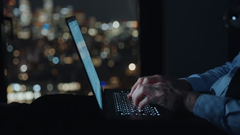 Businessman-working-at-laptop-computer-against-the-background-of-a-night-city