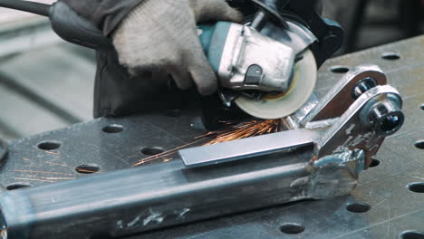 worker processing surface of metal part with angle grinder in workshop