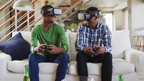Afroamerikanische-Teenager-Zwillingsbrüder-Auf-Der-Couch,-Die-VR-Headsets-Benutzen-Und-Lächelnd-Ein-Computerspiel-Spielen